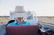 © Austockphoto - Female looking at computer outdoors with vehicle in background