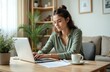 © miss irine - Young woman works at home office on laptop. Freelancer businesswoman uses Internet, works online. Attractive female at workplace desk, drinking coffee. Modern workspace, remote job, freelance life.
