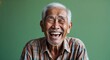 © sevenSkies - Indonesian elderly man on green plain bright background happy laughing hysterical looking at camera portrait banner with copy space ad concept marketing