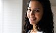 © Wavebreak Media - At home, Smiling woman with curly hair looking at camera, exuding warmth and confidence, copy space