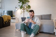 © Migma_Agency - Happy man using smartphone at home: relaxing with mobile phone