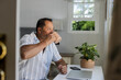 © Wavebreak Media - Senior Asian man enjoying coffee while working on laptop at home office desk