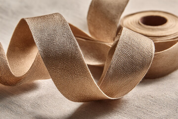 Aufkleber - Beige fabric ribbon, rolled and loosely arranged, showcasing texture and subtle sheen, representing elegance, simplicity, and craftmanship