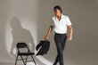 © Wavebreak Media - Confident man in white shirt holding jacket, walking past black chair in studio