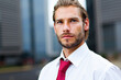 © Minerva Studio - Portrait of a confident businessman posing in front of modern buildings