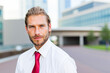 © Minerva Studio - Businessman wearing white shirt and red tie posing outside office building