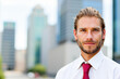 © Minerva Studio - Portrait of businessman smiling with skyscrapers in the background