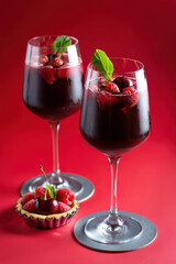 Aufkleber - Two glasses of dark red beverage garnished with raspberries and cherries alongside a raspberry tart.