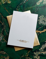 Aufkleber - Blank white card rests on gold envelope. Decorative flourish at the bottom. Green marble background has gold foliage design. Flat lay with copy space. Stationery for messages or greetings.