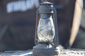 Poster - An old lantern sits on a rock in the outdoors.