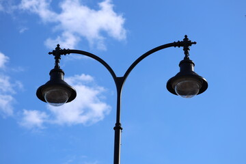 Poster - A single street light stands on a pole against a bright blue sky.