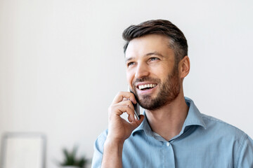 Poster - Business Communication. Smiling male office manager talking on cellphone at workplace, consulting client, smiling and looking away, copy space