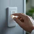 © Ika - Hand turning on a light switch with a small illuminated indicator