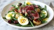 © Auon - Delicious Nioise salad seared tuna baby potatoes green beans olives and boiled eggs carefully plated on a white ceramic dish with a light dressing drizzle