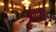 © Viktor - Hand holds VIP restaurant table invitation card. Premium elegant business dinner in fancy prestigious gold dining interior, copy space for luxury celebration event. Selective focus on gold VIP text.