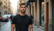 © Viktor - Handsome man in black t-shirt stands on city street. Male model portrait with stylish haircut and beard. Confident guy poses, looking at camera. Casual urban lifestyle.