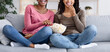 © Prostock-studio - Two black girls having fun at home, watching comedy and eating popcorn