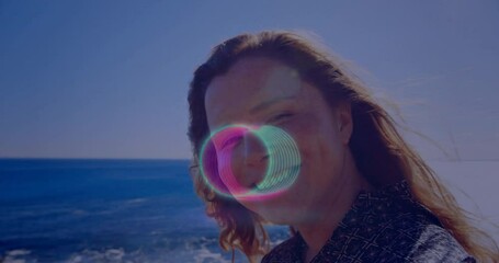 Poster - Person smiling by ocean with colorful circular animation overlay on face