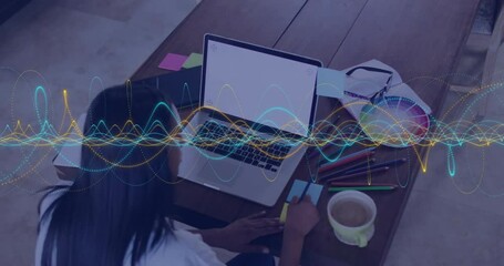 Aufkleber - Person working on laptop with colorful wave animation over wooden desk
