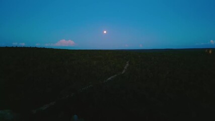Wall Mural - aerial drone view of the moon rising over the cerrado landscape at night, with rocks in the foregrou