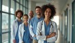 © natakot - A diverse group of healthcare professionals, including men and women, smiles confidently in a well-lit hospital corridor. Their camaraderie and dedication shine through, showcasing the unity and