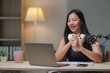 © Phimwilai - Young asian woman recording engaging podcast content in her home studio, utilizing a professional microphone and laptop while participating in an online interview