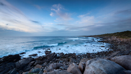 Poster - A serene coastal landscape featuring rocky shores and a tranquil ocean under a cloudy sky, evoking a peaceful natural ambiance