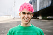 © Xavier Lorenzo - Young trendy man with pink hair laughing candidly standing outdoors. Portrait of fashionable gen z caucasian gay male at city street. People concept