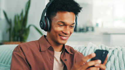 Poster - Happy, man and phone with headphones on sofa for sound subscription, watching online video and social media. Relax, person and smartphone in home for streaming podcast or listening to music in lounge