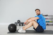 © New Africa - Athletic man with medicine ball resting on mat in modern gym