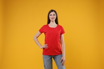 Wall Mural - woman wearing blank red t-shirt on orange background. mockup for design