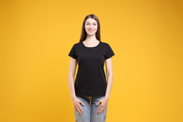 Wall Mural - woman wearing blank black t-shirt on orange background. mockup for design