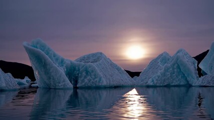 Aufkleber - Majestic icebergs reflect a stunning sunset over tranquil water in a remote arctic landscape