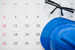 © pla2na - Flat lay of safety glass and blue worker helmet on blank white calendar background copy space. Payday, working or training schedule for worker or employee, labor day, holiday and so on concept.