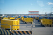 © Connect Images - Yellow carts labeled dangerous goods at an industrial area with a building and blue sky.