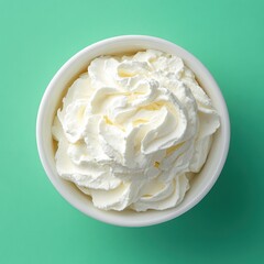 Poster - Aerial view of creamy whipped topping in a white bowl against a vibrant green background offering a sweet and delightful treat