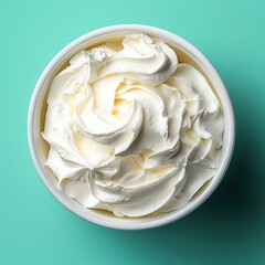 Poster - Aerial View of Creamy Whipped Topping in White Bowl on Turquoise Background Smooth Texture and Swirls