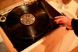 © Connect Images - Hand adjusting the tonearm of a vintage turntable with a black vinyl record.