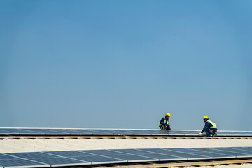 Wall Mural - two engineers install solar panels on a rooftop, wearing safety gear and helmets. the scene showcase
