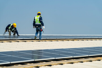 Wall Mural - two engineers install solar panels on a rooftop, wearing safety gear and helmets. the scene showcase