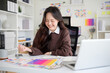 © wattana - Young creative woman analyzing color palettes and working on branding in a modern office.