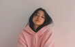 © Marina - Portrait of a young East Asian woman with straight hair and soft pink hoodie, white background, no hands, peaceful vibe