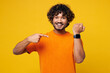 © ViDi Studio - Young surprised shocked happy Indian man wear orange t-shirt casual clothes point index finger on smart watch with blank screen isolated on plain yellow background studio portrait. Lifestyle concept.