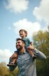 © miss irine - Happy father carries son on shoulders in park. Man and young boy laughing, enjoying fun time together outdoors. Cheerful kid and dad spend weekend, holiday. Family relationship concept.