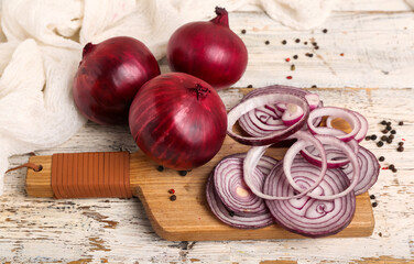 Wall Mural - Board with slices of fresh red onion and peppercorn on white wooden background