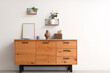© Pixel-Shot - Chest of drawers, picture frame and shelves with houseplants on white wall in living room