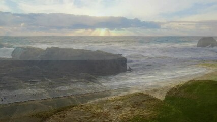 Poster - Crashing waves against rocky coastline under cloudy sky with sun rays filtering