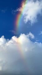Wall Mural - Vertical video of faint rainbow in the clouds, blue sky 