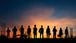 © Windy Junes - Row of human silhouettes standing side by side against orange sunset sky with construction equipment and vertical metal rods visible on frame edges