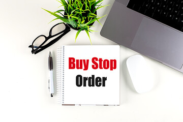 Poster - Notebook with the words buy stop order on white desk with pen, glasses, laptop, mouse and green plant 